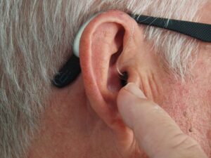 older mans ear being touched by his finger
